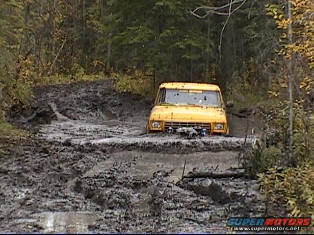 Yellow 1979 Ford F-250 mud bogger navigating a deep mud pit