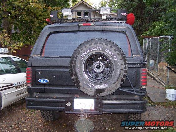 1996 Ford Bronco rear view with spare tire mounted on tailgate, roof rack with lights, and tow hitch