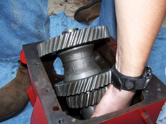 hand reaching into red housing with large metal gears