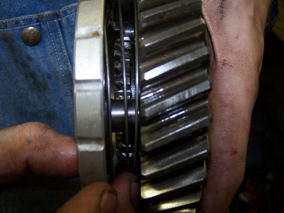 Close-up of a large metal gear with teeth, held by hands