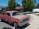 1989 Ford F-250 - A dusty red Ford pickup truck is parked in front of houses, with two other vehicles visible on the street.