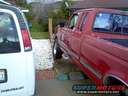Red pickup truck, side view, parked next to a white van