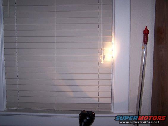Black gear shift knob in front of window blinds