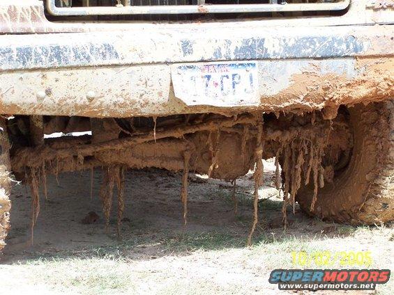 Mud covers the undercarriage and license plate of a vehicle