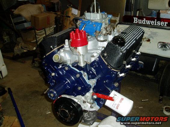 Ford V8 engine with blue painted block, red distributor cap, and black valve covers reading "Powered by Ford"
