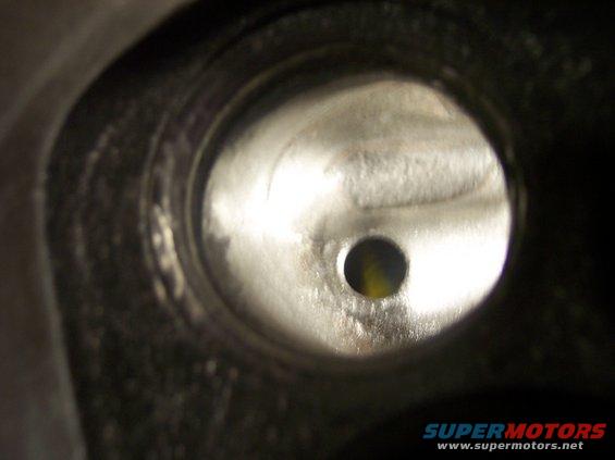 Close-up view inside an engine cylinder head port, showing a circular opening