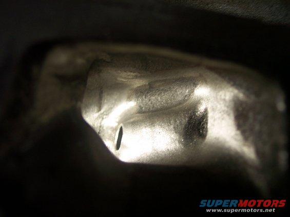 Close-up of a metallic engine component with a slot, dimly lit