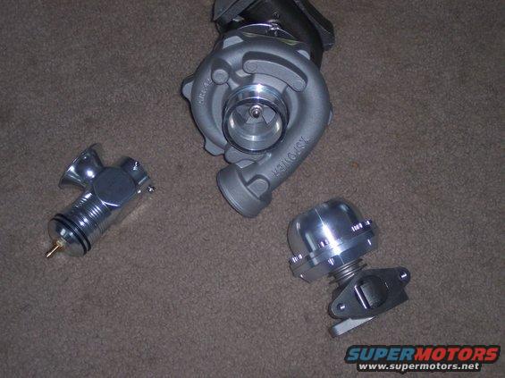 Turbocharger and two aftermarket blow-off valves on a carpeted surface
