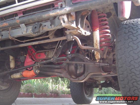 Undercarriage of a red SUV with visible suspension components, differential, and tires