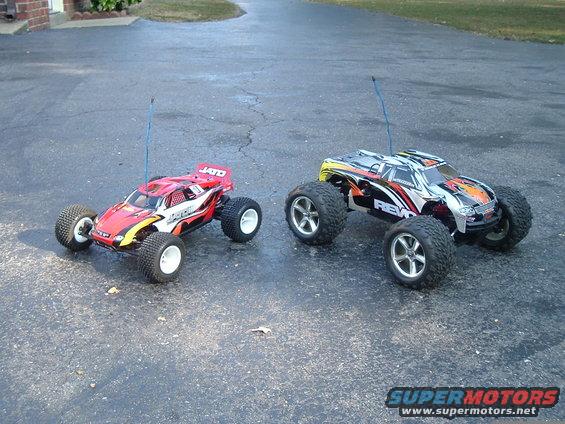 Two RC monster trucks, one red and white, the other black, white, and yellow, parked on asphalt