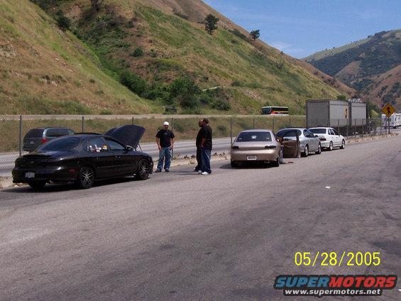 1998 Mercury Sable and other cars parked on highway shoulder with people standing around