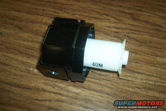 Black plastic automotive part with white cylindrical component marked '40M'