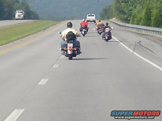 Group of motorcycles riding on a highway with cars in the distance