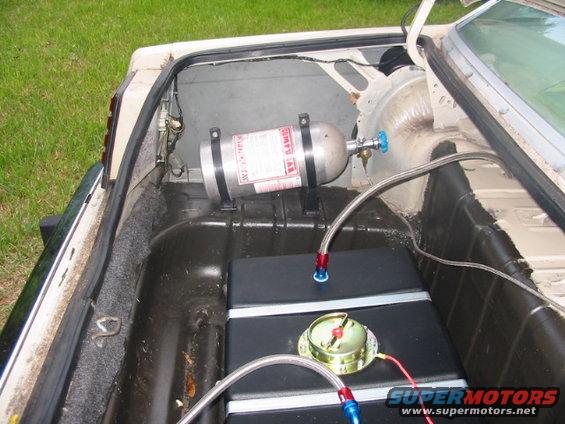 Car trunk with a nitrous oxide tank mounted above a fuel cell, connected by braided hoses