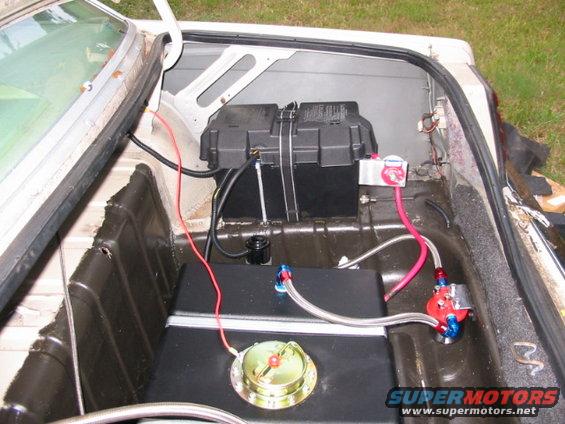 Car trunk interior with a black fuel cell, battery, and red fuel lines