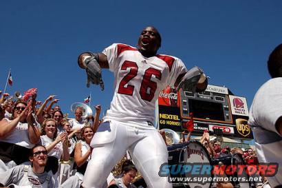 Football player in uniform #26 celebrating with crowd and scoreboard in background