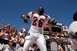 1996 Ford Mustang - A football player in a white and red uniform celebrates with fans while a scoreboard and band are visible.