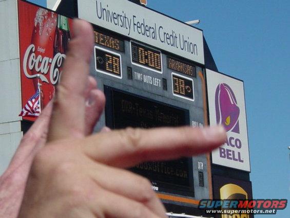 Scoreboard with Coca-Cola and Taco Bell ads, a hand in the foreground