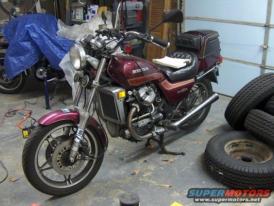 Maroon 1983 Honda GL650I Silverwing Int motorcycle with a black trunk and chrome accents, parked indoors