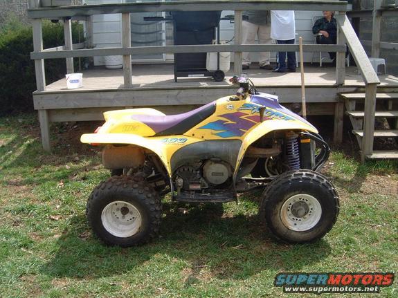 1996 Polaris SCRAMBLER 400 ATV parked on grass in front of a wooden deck
