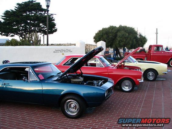 Blue 1968 coupe with hood open, parked in a line with other cars