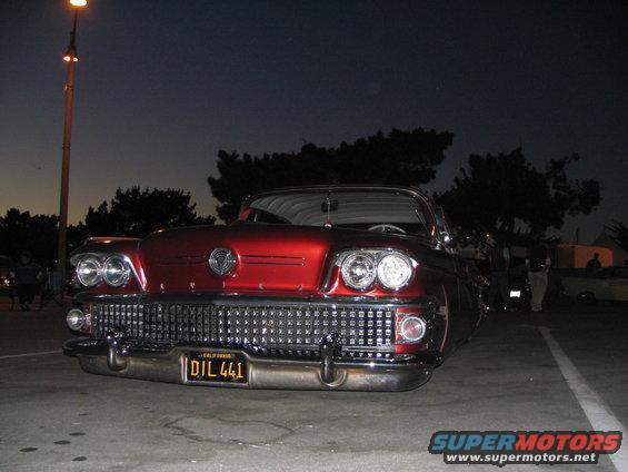 Red vintage car with chrome grille and dual headlights. California license plate DIL 441