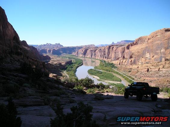 Black pickup truck on rocky overlook with canyon and river