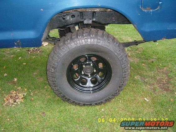 1979 Ford F-150 rear wheel, leaf springs, and fender well. Black off-road tire on a black rim