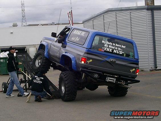 Blue 1985 Ford Bronco with lifted suspension and off-road tires, rear view