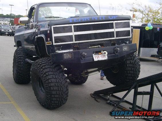 Lifted black pickup truck with large tires and a custom bumper. Blue text on the hood reads 'TEAR IT UP'. License plate PVK-686 is visible