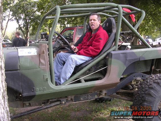 Guy in red jacket sticking tongue out in a camo Jeep. Another Jeep is behind it