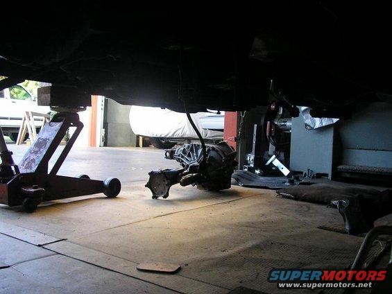 Transmission removed and resting on the floor under a vehicle on a jack