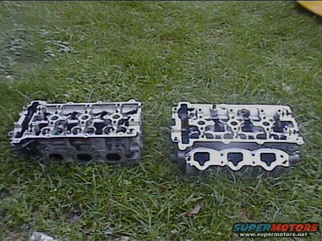 Two engine cylinder heads on grass, one on the left and one on the right