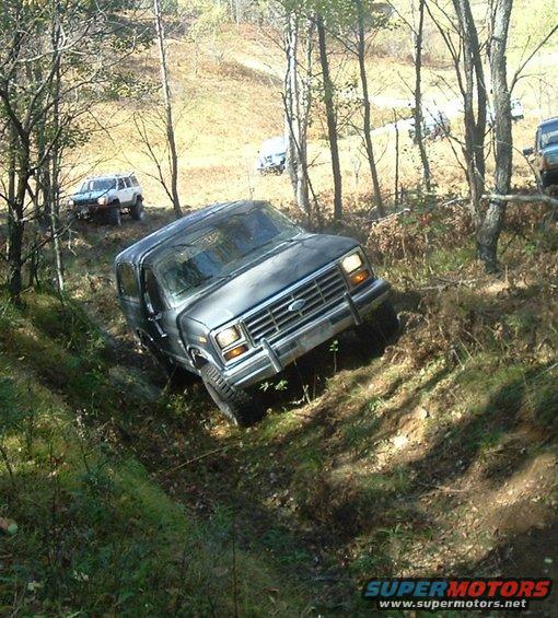 Dark SUV descending a dirt path, front grille visible, tires on dirt