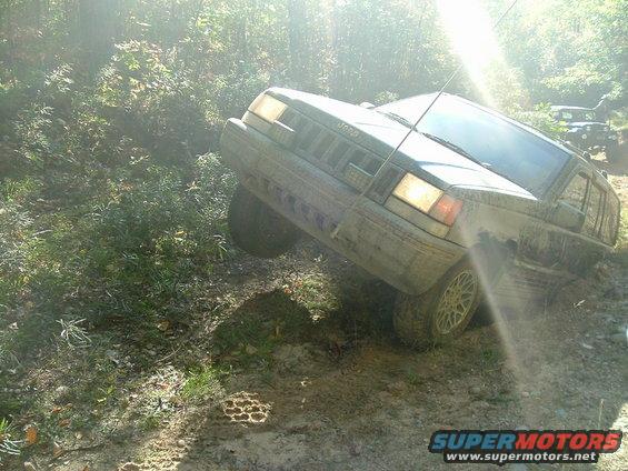 Dark green Jeep Cherokee XJ climbing a muddy hill