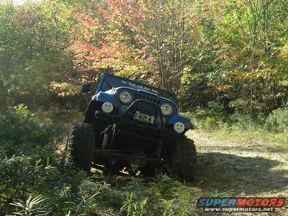 Blue Jeep off-roading on a dirt path with trees in the background. Text on windshield reads 'For Truth with God's Call'