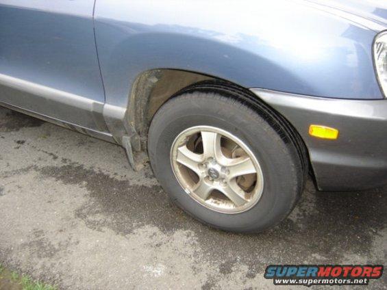 Front wheel and fender of a blue Hyundai Santa Fe, likely from the early 2000s