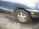 1999 Ford Taurus - Close-up of the front wheel and fender area of a blue SUV, showing the tire and alloy rim.