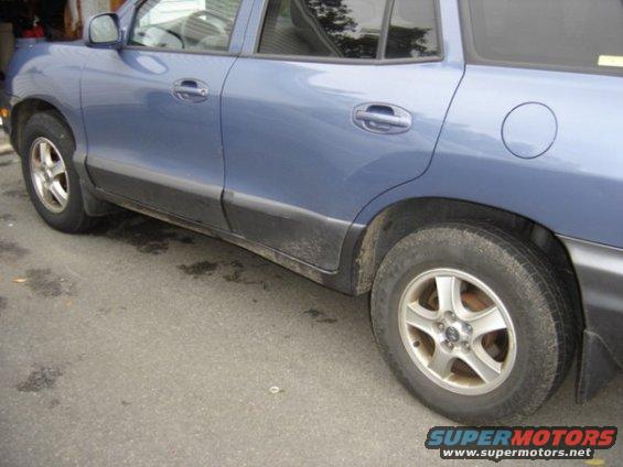 Blue SUV parked on asphalt, showing side doors, rear wheel, and fuel door