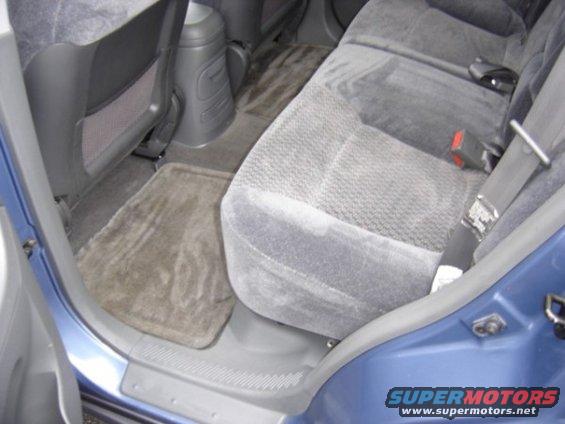 Blue vehicle interior showing rear seats, floor mats, and center console