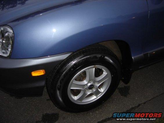 Blue SUV front fender and wheel with black trim and amber turn signal