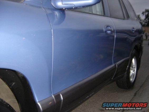 Side view of a blue SUV showing the door, black trim, and wheel