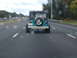 1979 Ford Bronco - A teal Jeep Wrangler is seen driving on the highway from behind, with a spare tire mounted on the tailgate.