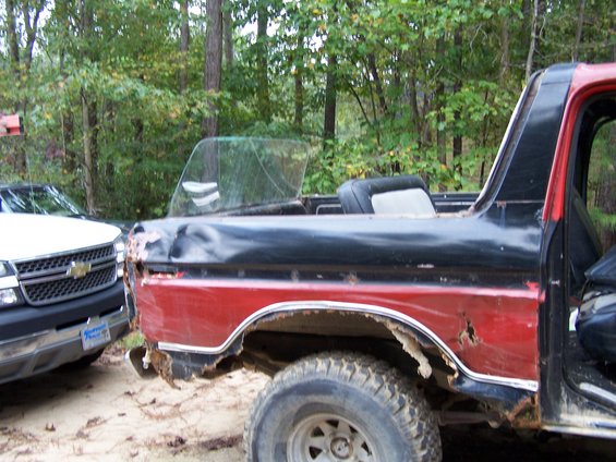 1979 Ford F-150 side view, red and black paint, significant rust and body damage