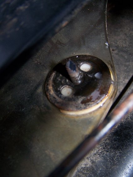 Close-up of a rusty metal bracket with a bolt and rubber grommets
