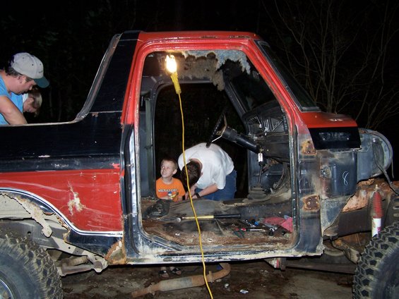Red and black truck cab interior, open doors, people working on project