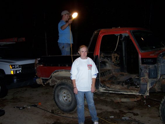Red pickup truck with no doors or interior, seen from the side at night
