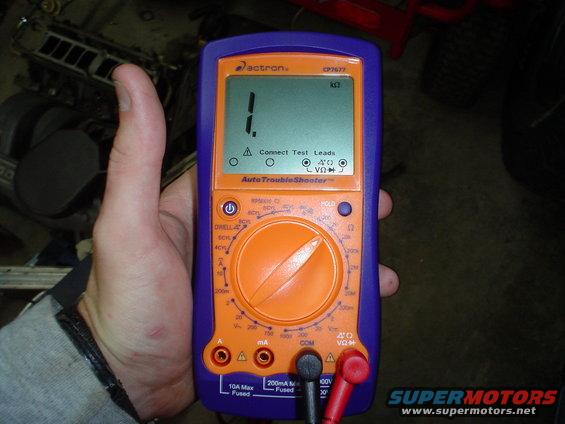 Hand holding a purple and orange multimeter displaying '1.' and 'Connect Test Leads'