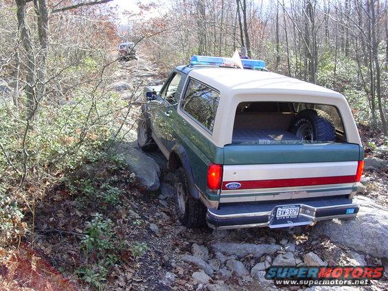 Green and tan Ford Bronco on a rocky trail, another vehicle ahead
