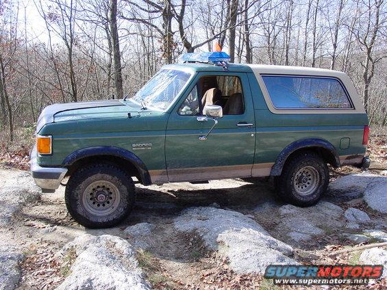 Green Ford Bronco with tan top on rocky terrain